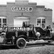 View of a hook and ladder truck in Denver, Colorado. A sign on a brick building reads: "Garage."