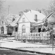 View of single family residences at the corner of Arapahoe and Downing Streets in the Five Points neighborhood of Denver, Colorado. Architectural features include chimneys, arched windows, an ocular window, decorative brick coursing and covered porches with square post and spindle supports.