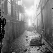 Interior pipe railed metal balconies front cell blocks at the State Penitentiary in Canon City, Colorado, after the riot of 1929. Doors are open, fire damage consists of debris and holes in the roof.