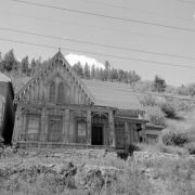 View of the Lace House, Black Hawk, Colorado, an example of Victorian Carpenter Gothic architecture with board and batten siding, steep pitched roof with finials, arched-pointed windows, elaborate one-story veranda with balustrades, and decorative (gingerbread) bargeboard gable trim. The name "Lace" comes from the delicate, lacy detailing; the house was later refurbished and converted to a museum.
