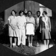 African American women, staff members and visitors pose together (includes "Mother" Gross the camp cook, and Mary Wood aka "Woody") at Camp Nizhoni in Lincoln Hills (Gilpin County) Colorado. They wear dresses, pants, shorts, blouses; one wears a scarf.