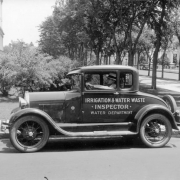 A man poses in a Water Department service truck by the Colorado State Capitol building in Denver, Colorado; lettering on the truck reads: "Irrigation & Water Waste Inspector, Water Department."