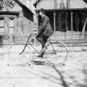 A man rides a bicycle by brick houses with covered porches and a bay window in Denver, Colorado.