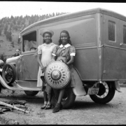 Four African American teenage campers stand by a truck at Camp Nizhoni in Lincoln Hills (Gilpin County), Colorado. One camper holds a patterned, wide-brimmed hat. The license plate on the Ford truck reads: "Colo. 1937  1-82702."