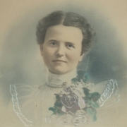 Bust portrait drawing of Emma Glea Woodruff, identified as Apple Queen of Colorado. The young woman wears probably a lace shirt with a ruffled collar, a brooch and a floral corsage.