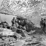 Four soldiers, from a unit in support of the Tenth Mountain Divisin Infantry, fire heavy artillery from beneath a camouflage.