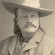 Studio portrait of Pawnee Bill (Gordon W. Lillie), with a moustache, long hair, and a cowboy hat.