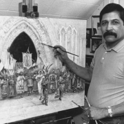 Painter John Flores, a Chicano artist from Denver, Colorado, poses with paint brushes as he works on a painting.