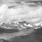 Patches of snow remain on Arapaho Peak during the summer in This distant view from the head of Gamble Gulch in Gilpin County, Colorado. Arapaho Peak is on the border of Boulder and Grand Counties. Cumulus and cirrus clouds fill the sky.