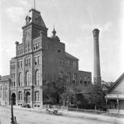 The Milwaukee Brewery Company was established in 1859 by James Endlich at 10th and Larimer Streets in Denver, Colorado. In 1860, the brewery was sold to John Good, who enlarged it and renamed it after the Tivoli Gardens in Copenhagen. In 1901, the brewery merged with the Union Brewing Company to form the Tivoli-Union Brewery. The plant shown here continued to operate until 1969, producing Denver Beer. Several horse-drawn  wagons are on the dirt street in front of the building.