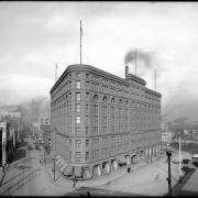 Exterior view of Brown Palace Hotel, Denver, Colorado; shows overview of hotel, streets, street car tracks, and wagons at the intersection of Broadway and 17th (Seventeenth) Street; backside of Equitable Building distant left and Denver High School, distant right.