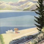 View of Lake Pend Oreille in Idaho shows a Northern Pacific train near the shore with a boat and boathouse nearby. Mountains are in the distance.