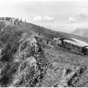 Mount McClellan's summit (14,007 feet) via Argentine Central Railway, Colorado; shows engine and passenger cars parked with large group of sightseers at summit and in cars, passenger cars retouched to reflect name of "Gray's Peak Route," narrow gauge track, and Rocky Mountains in background.