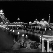 The White City, later called Lakeside Amusement Park, during a summer evening, Lakeside, Colorado near Denver; night time view of amusement park area with illuminated rides, sidewalks and buildings, people at ticket gazebo, the Big Splash, Casino Theater and Cafe.