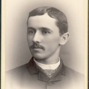 Studio bust portrait of Edwin Stebbins Kassler, a senior at Denver High School in Denver, Colorado. Kassler's hair is parted in the middle and he has a moustache. He wears a morning coat, a cravat with a tie pin made to look like an insect, and a shirt with an upright collar.