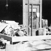The trunk of a cottonwood tree and debris are pushed through the display window of the Pierce Seed Company at 216 W 4th (Fourth) Street after an Arkansas River flood in Pueblo, Colorado. Part of the wall and the window frame have collapsed.