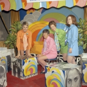 Women pose for a publicity shots near pop-art cubes in Denver, Colorado. A sign on the wall reads: "Columbia Savings," and signs on the cubes read "The Finanswer." The women wear mini-skirts and neckties.