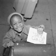 An African American (Black) boy mails a letter addressed to "Santa Claus" in (probably) Denver, Colorado.