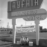 Men pose with a sheep by the Mayfair Shopping Center sign (in moderne letters) in Denver, Colorado; another sign reads: "Grand Champion Lamb, Free To Be Given To The Person Who Guesses The Nearest Dressed Weight. Register Your Guess at King Soopers Meat Dept."