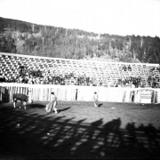 The bullfight on August 24 or 25, 1895, (the third day planned was cancelled) takes place in the bullring built at the race track in Gillett, Colorado, for the occasion. Joe Wolfe was the organizer of the event. The bull is coming out of the gate and the Mexican matador, probably  Jose Marrero, waves his cape; another bullfighter is in the ring. Spectators are in the stands behind the wood fence.