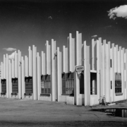 View of a business at 4050 Globeville Road in Globeville, Colorado. The building is made with precast concrete twin "T" sections, and has an irregular roof line. Segmented overhead doors and a loading dock are along the side.