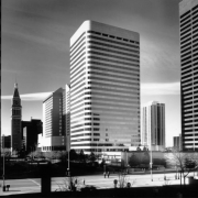 View of downtown Denver, Colorado; shows the Westin Hotel (with light reflections), the May D & F clock tower, and Larimer Place Condominiums. Office buildings include Denver National Bank (round corners). Pedestrians walk on 17th (Seventeenth) Street; the Central Bank Building is in the distance.