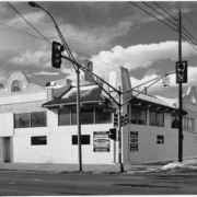 View of a building (formerly the Ball Park bathhouse) at 101 South Broadway Street (at West Bayaud Avenue) in the Speer Neighborhood of Denver, Colorado. The brick building has mission style pediments, corner turrets, and shingle pent roofs. Movie theater signs and marquee read: "Kitty's South," and "Matties."