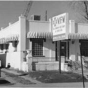 View of a V.F.W. Post at 1545 South Broadway Street in the Overland Neighborhood of Denver, Colorado. The stucco finish building has glass block windows, awnings, urns, steps, and a sign: "V.F.W. So. Denver Post 2461 & Ladies Aux."