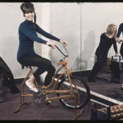 Women pose on exercise equipment in front of a wall mirror at the cub house in the Green Mountain Townhomes complex in Lakewood, Colorado. One woman sits on an exercise bike, another sits on the edge of a roller massager.