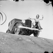 A woman poses on the fender of an automobile probably in Colorado.