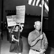 Protestors who include Lindsay Jones and Mrs. Kenneth Gott march in a picket line near the Denver Public Library at 1331 Broadway in the Civic Center neighborhood of Denver, Colorado. The protestors hold signs that read: "Reducat[ion] is Brain Washing" and "American Boys Being Drafted While Commie Propagandize Their Children."