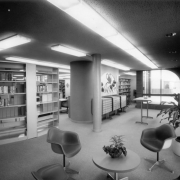Interior view of the Bear Valley Branch of the Denver Public Library in the Harvey Park South neighborhood of Denver, Colorado; decor includes molded plastic chairs, curved window frames, a dracena plant, and card catalog cabinets.
