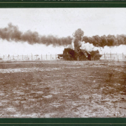 A staged collision of Union Pacific, Denver and Gulf Railway Company engines number 154 and 153 on September 30, 1896 in the Elyria-Swansea neighborhood of Denver, Colorado. Clouds of smoke fill the sky and spectators run or stand nearby.