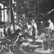 Interior view of a Great Western Sugar processing facility in Colorado; men work by vats and pipes.