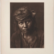 Bust portrait of a Native American (Navajo) boy in a cloth headband and a probably woven shirt and jacket.