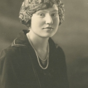 Frances Marie Kober poses for her South High School senior portrait in Denver, Colorado. Kober's hair is styled in a curly bob with a barrette clip and she wears a sailor style blouse with piping on the lapels, and a double strand pearl necklace.