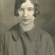 Evelyn Tunstall poses for her South High School senior portrait in Denver, Colorado. Tunstall's hair is styled in a bob with a barrette clip and she wears a frock with a rounded collar and a row of pearl buttons on the side.