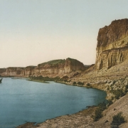View of eroded striated bluffs and cliffs, the pillar Tollgate Rock and The Palisades on Green River in Sweetwater County, Wyoming.