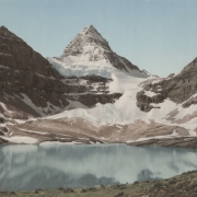 View of Lake Magog, a glacier, and Mount Assiniboine in Mount Assiniboine Provincial Park in British Columbia, Canada.  Shows an alpine lake at the foot of rugged snow covered peaks.