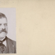 Studio portrait of a man identified as D. Noyer, a resident of Georgetown (Clear Creek County), Colorado.  He wears a wool sack style jacket, matching vest, a shirt with an upstanding collar and a silk necktie. He wears his hair combed back and has a full mustache.
