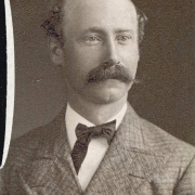 Studio portrait of Charles A. Martini, probably a resident of Georgetown (Clear Creek County), Colorado. He wears a plaid coat with wide lapels a vest and a bow tie. He is balding and his dark hair is parted and curly on the side. He has a full, waxed mustache.