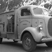 A Ford Coors delivery truck parks on a Colorado street with cases  of beer showing through side door. Lettering on truck reads: "Adolph Coors Co. Denver" and "Coors Brewer of Fine Beer."