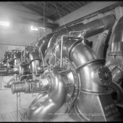 Interior view of Orchard Mesa ditch power plant, Mesa County, Colorado; shows four large turbine pumps, brick building, and pressure gauge.