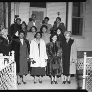 Thirteen women, presumed to be members of the Negro Woman's Club Association of Denver, stand on the front porch of the organization's original headquarters building at 2357 Clarkson Street.