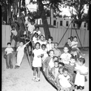 Thirty-Five students of the George Washington Carver Day Nursery school pose on the playground side at the school's 2357 Clarkson playground. One child hangs upside-down from underneath the slide.