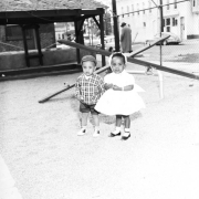 Two toddlers in fancy dress play in front of the seesaws, on the George Washington Carver Day Nursery Playground at 2357 Clarkson.