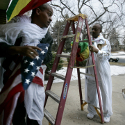 Debre Salam Medhanealem Ethiopian Orthodox Tewahedo Church members Ashenafi Admassu, left, and Melaku "Angel" Hailegiorgis, right, hang an American flag along with a banner with the Ethiopian colors as they celebrate the inauguration the church