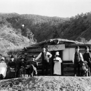 Patrons and employees stand outside Fred Barlow's Grand Springs Hotel, a one-story log cabin with a sod roof in the town of Glenwood Springs (formerly known as Defiance), Colorado, in Garfield County. Participants in the wedding celebration are thought to be (l.to r.): Dolly Barlow (bride), Ella Barlow, Mrs. E.M. Landis, Fred Barlow, John Blake, Chang (Chinese cook), William Landis (groom), M. V. Blood, and Perry Malaby.