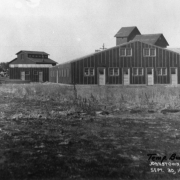 View of the temporary bunkhouses of migrant workers in Johnstown, Colorado, in Weld County show warehouse-shaped buildings with several entry doors.