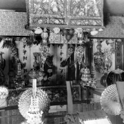 Interior view of a room decorated to commemorate the Chinese New Year in Denver, Colorado. Tables covered with cloth hold fruit displays and ceramic vases. Paper lanterns hang from the ceiling.